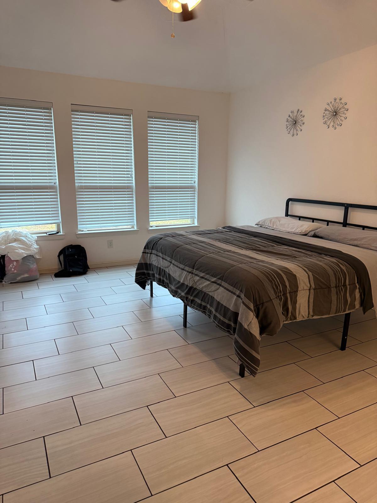 Guest bedroom with a made bed and clean tile floors after a Houston short-term rental turnover clean